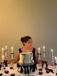 a woman sitting in front of a cake with candles on it