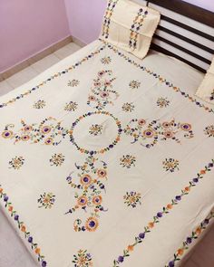 a bed covered in a white bedspread with colorful flowers on it