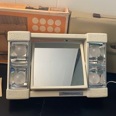 an old fashioned white mirror sitting on top of a table next to boxes and other items