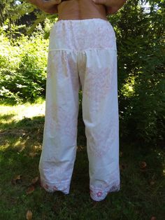 Delicate, vintage lace of pink and white trims the cuffs of these loose fitting, wide legged Palazzo pants. The crisp, white fabric has a pink floral design which harmonizes beautifully with the lace trim.A draw string waist ensures a comfortable and adjustable fit.One sizeMade in Massachusetts from 100% repurposed cotton textile and vintage lace1 of 1 White Bohemian Cotton Harem Pants, White Bohemian Bottoms With Lace Trim, White Wide Leg Bottoms With Lace Trim, Pink Bottoms With Lace Trim For Spring, Pink Lace Trim Bottoms For Spring, Spring Pink Bottoms With Lace Trim, Cotton Wide-leg Bottoms With Lace Trim, Wide Leg Cotton Bottoms With Lace Trim, Pink Cotton Spring Harem Pants