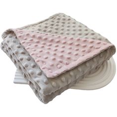 three blankets stacked on top of each other in front of a white plate with a pink and gray polka dot design