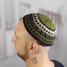 a man with a tattoo on his neck wearing a green and black knitted hat