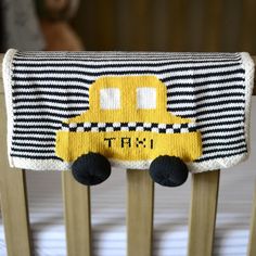 a crib with a black and white striped pillow on it's side that has a yellow taxi motif