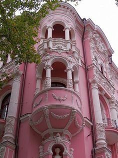 a pink building with ornate balconies on the front and side windows is shown