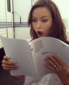 a woman reading a book while sticking her tongue out