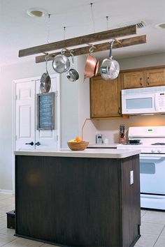 a kitchen with an island and pots hanging from the ceiling over it's stove