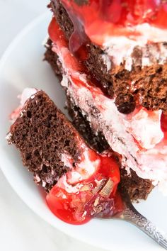 a piece of cake on a white plate with a fork next to it and some cherries