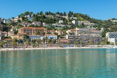 the beach is lined with houses and buildings on top of a hill above the water