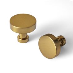 two brass knobs on white background with one in the center and one in the back