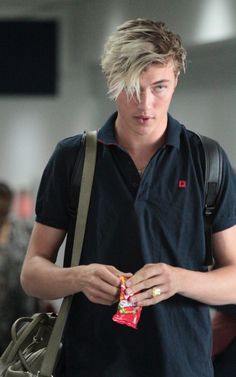 a young man with blonde hair is holding a candy bar