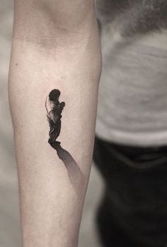 a man's arm with a small tattoo on it, and the shadow of a person holding an umbrella