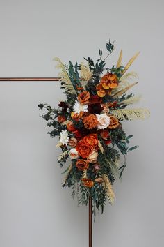 an arrangement of flowers on a stand against a wall