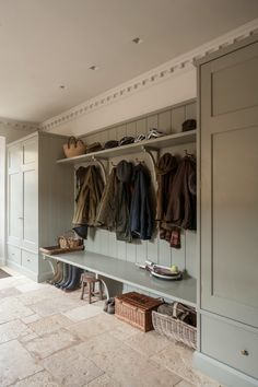 a coat rack filled with lots of coats and shoes next to a bench in a room