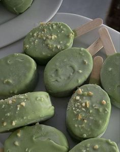 some green desserts are on a plate and ready to be eaten with wooden skewers