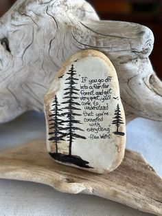 a rock with a poem written on it sitting next to a wooden log and tree