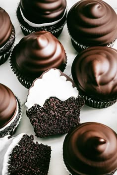 chocolate cupcakes with frosting and sprinkles on a white surface