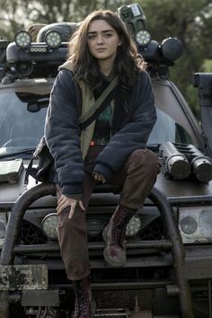 a woman sitting on the hood of a vehicle