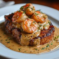 a white plate topped with meat covered in gravy and shrimp on top of sauce