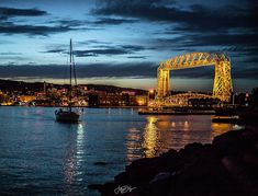 a boat is in the water at night near a bridge with lights on it's sides