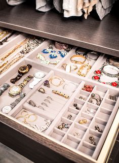 a drawer filled with lots of jewelry on top of a wooden table