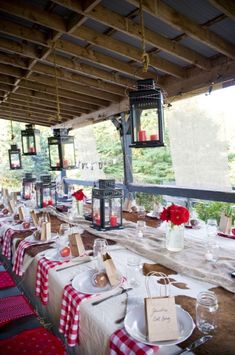 an outdoor dining area with red and white checkered tablecloths, lanterns and candles