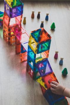 a child playing with colorful plastic blocks on the floor