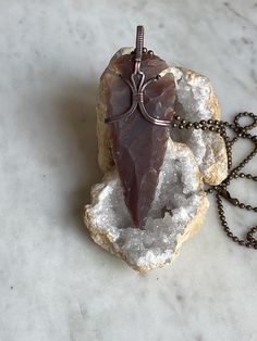 Beautiful wire wrapped and hand woven pendant in antiqued copper with an eye catching Agate Arrowhead. The copper has been patinaed to give it an antiqued look and then hand polished for a final shine. Agate is an excellent stone for rebalancing and harmonising body, mind and spirit. It cleanses and stabilises the aura, eliminating and transforming negativity. Agate enhances mental function, improving concentration, perception and analytical abilities. This pendant series is a collaboration with my son. He has been requesting a pendant a young man could wear for a while now. I look forward to more collaborations with him in the future. All purchases have an 20" black nylon waxed cord and 24" antique copper ball chain necklace included. Wire Wrap Arrowhead, Arrowhead Necklace, Ball Chain Necklace, Beading Wire, Wrapped Pendant, Black Nylon, Wire Wrapped Pendant, Copper Jewelry, Ball Chain