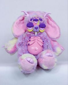 a pink and purple stuffed animal with cupcakes in its mouth