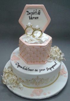 a wedding cake with two rings on top and congratulations written on the side, sitting on a platter