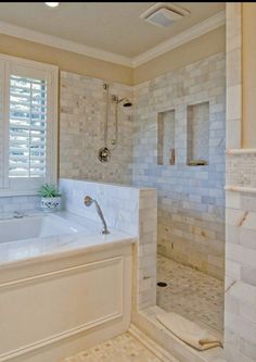 a large white bath tub sitting next to a walk - in shower under a window