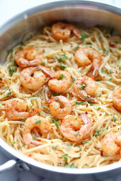 pasta with shrimp and parmesan cheese in a skillet on a wooden table