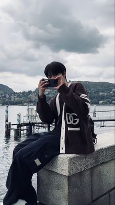 a person sitting on a ledge with a cell phone up to their ear, taking a photo