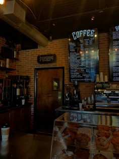 the inside of a coffee shop with menus on the brick wall and pastries behind it