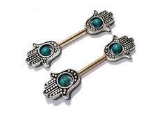 two metal barbells with turquoise beads and wings on them, one has a green stone in the middle