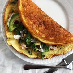 an omelet is on a white plate next to a fork