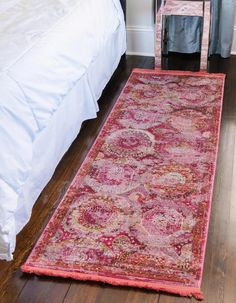 a large pink rug is on the floor next to a bed