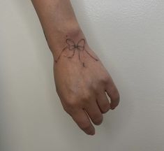 a woman's hand with a bow tattoo on her left wrist and the other arm