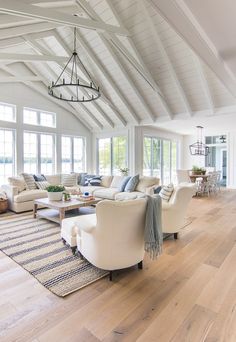 a large open living room with white furniture and wood flooring on the hardwood floors