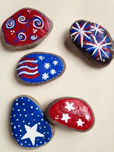 four painted rocks sitting on top of a white surface