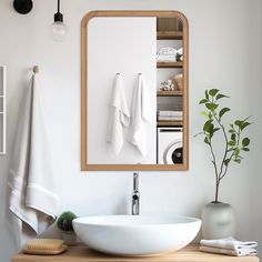 a bathroom sink sitting under a mirror next to a wooden shelf with towels on it