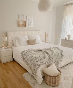 a bedroom with white walls and wood flooring has a large bed covered in blankets