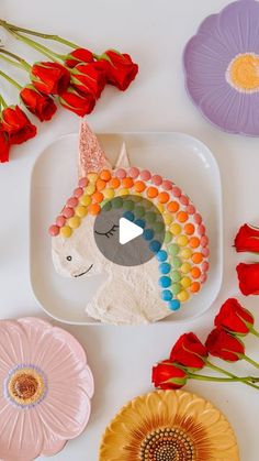 a white plate topped with a cake next to colorful flowers and paper plates on top of it