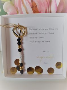 a card with a key hanging from it's side in front of some flowers