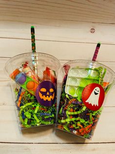 two plastic cups filled with candy and halloween decorations