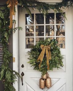 a wreath on the front door of a house with bells hanging from it's side