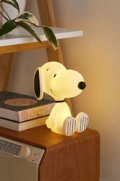 a dog lamp sitting on top of a wooden table next to a book and radio