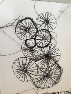 an art piece made out of wire with circles in the shape of flowers on it