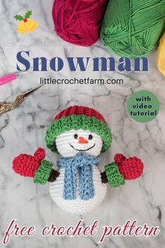 a crocheted snowman is sitting next to balls of yarn