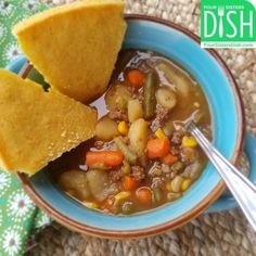 a blue bowl filled with soup and cornbread on top of a table next to a green napkin