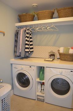 a washer and dryer in a laundry room with clothes hanging on the rack